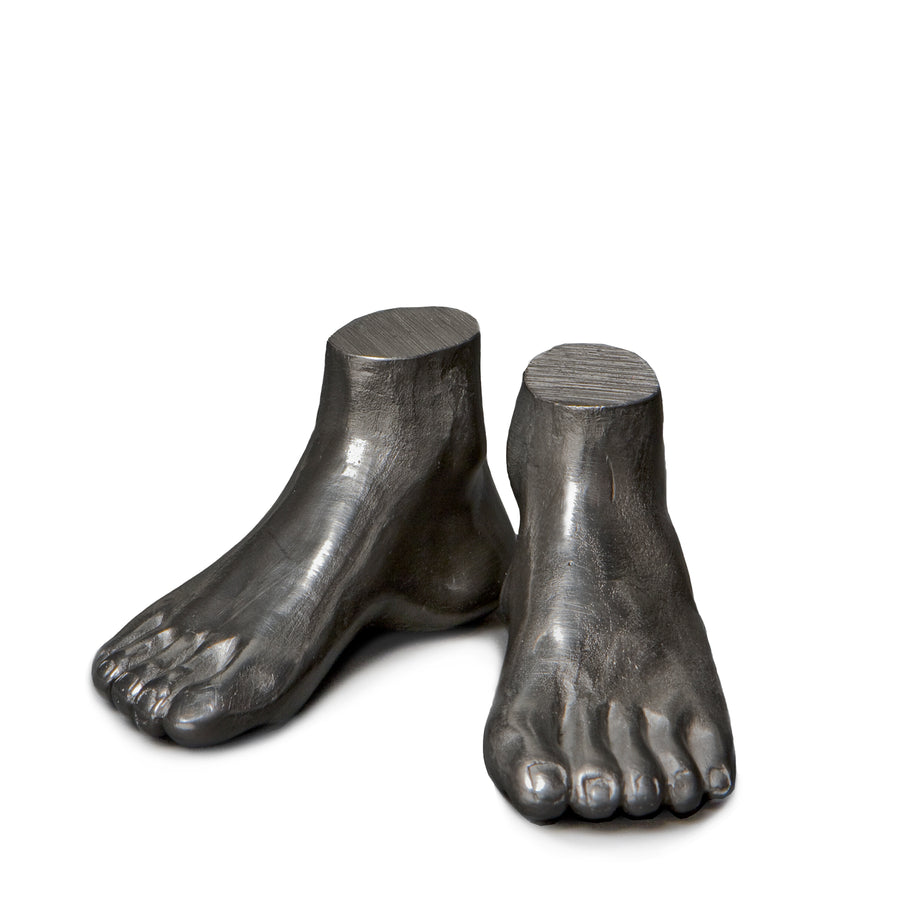 These are a pair of seperate small deep grey graphite feet. They start from above the ankle and are carved down to the toes in incredible detail. You have the indentations of the nails, arch and undulations between each toe. Above the ankle is a sharp flat plateau ending the foot sculpture.  